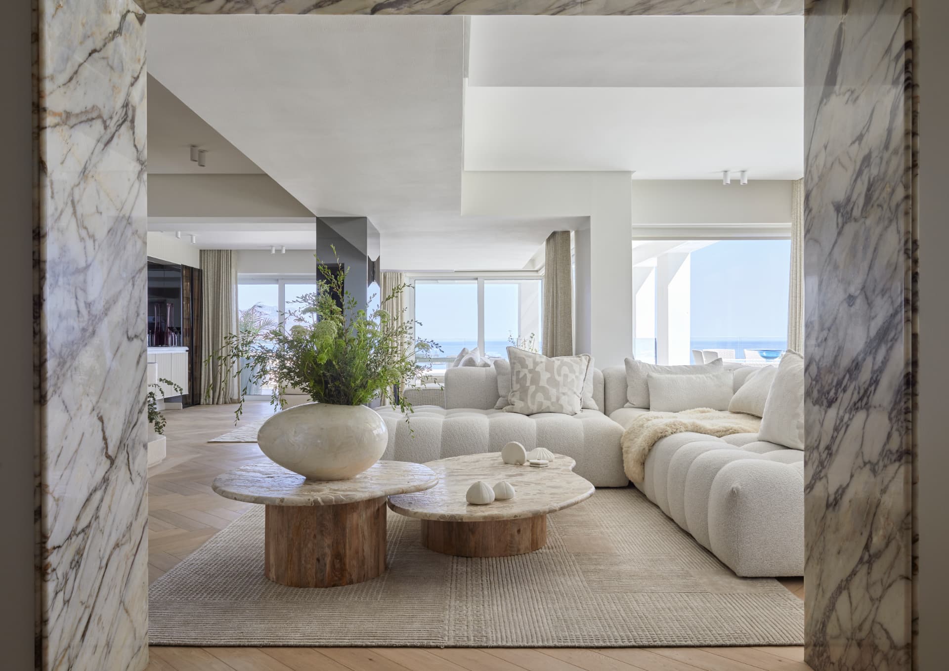A Zoya handcrafted rug in a bright sea-view living room framed by a marble doorway